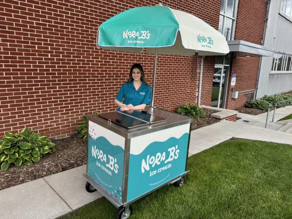 Girl standing behind a nora b's ice cream cart rental in Florida