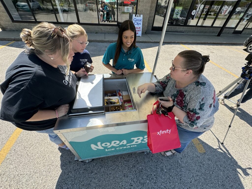 Women standing around nora b's ice cream cart rental in Florida